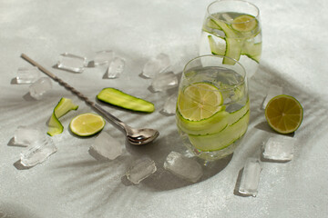 Wall Mural - Refreshing detox cocktail with cucumber and limes.Summer cocktail with palm leaves shadow.Close up of healthy drink.