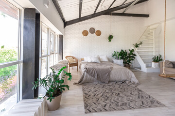 Luxury bedroom design in a rustic cottage in a minimalist style. white walls, panoramic windows, wooden elements of decoration on the ceiling, rope swings in the middle of a spacious room