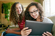 © Tetra Images - Mixed race teenage girls relaxing on sofa