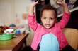 © Tetra Images - Mixed race baby girl with arms raised at table