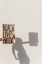 Hand Holding Black Lives Matter Sign, Shadow Of Person On The Wall