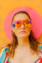 Portrait Of Woman Wearing Glasses With Colourful Pom Poms Covering Her Eyes