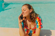 © VISTA by Westend61 - Portrait of happy woman on the phone sitting at poolside