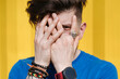 © VISTA by Westend61 - Young man standing in front of yellow wall, hiding face behind his hands