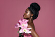 © Beauty Agent Studio - Profile portrait of young beautiful African American model posing with lily flowers against pink background