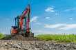 © edojob - A small excavator is building a new road on a green field. copy space