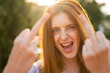 © Westend61 - Portrait of laughing redheaded woman giving the finger