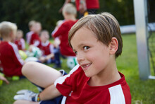 Portrait Of Playful Boy With Soccer Team In Background On Field