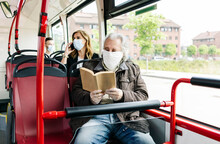 Senior Man Wearing Protective Mask In Public Bus Reading A Book, Spain