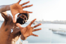 Black Man With Beanie And Face Mask, Looking Through His Hands