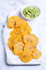 Fried tostones, green plantains, bananas with guacamole sauce