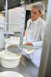 © Westend61 - Cheese factory, female worker with cheese molds