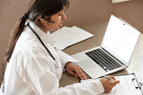 Indian telemedicine doctor wear headset consulting patient by online video call. Female gp communicating with client in remote telehealth conference video chat in India. Virtual visit in zoom meeting.