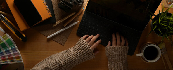 Poster - Female designer typing on tablet keyboard on worktable with supplies, painting tools and decorations