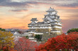 Himeji Castle and red maple leaves in evening sunlight and twilight sky in Himeji city, Hyogo prefecture of Japan.