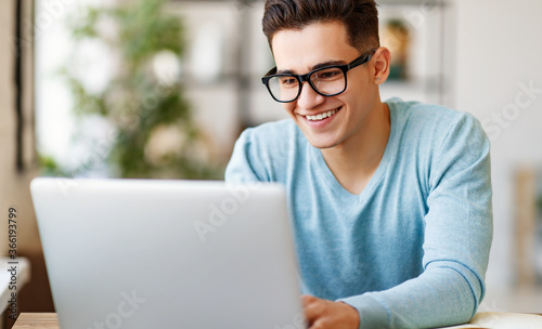 Fotomural Cheerful ethnic student using laptop at home.