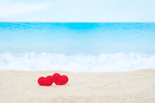 Two Red Hearts On White Sand Beach With Blurred Blue Sea