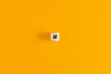 Hashtag Symbol On Wooden Cube Against Yellow Background. Overhead View With Copy Space.