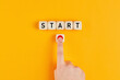 The word start on wooden cubes with a male hand pressing the start button. To make a new start in life, business, education or career concept.