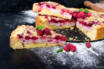 raspberry pie with ripe raspberries in homemade cooking with cottage cheese cut into pieces on a dark background, top view place for text