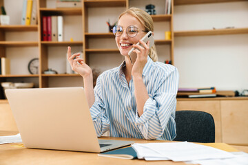 Wall Mural - Image of businesswoman talking on cellphone while working with laptop