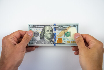 Man's hands holding one hundred dollar bill