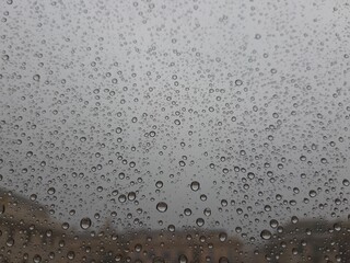 Beautiful photography of the waterdrop over the window. Indoor panoramic view to the city after rain.