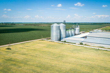 Aerial view of a modern grain elevator in a green wheat field.