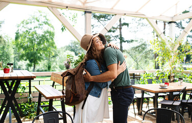 Wall Mural - happy couple greeting outdoors on terrace restaurant, hugging.
