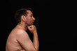 © ARVD73 - Side view thoughtful undressed middle man demonstrating reverie. Black wall