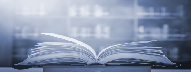 Poster - ancient book opened on a wooden table with a sparkling golden background. With magical power, magic, lightning around a glowing book In the room of darkness