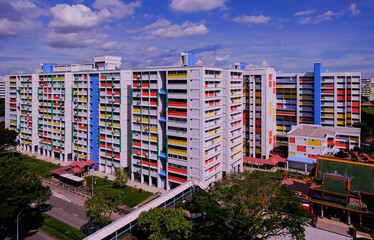 Wide angle, panoramic view of typical colourful public housing (HDB flats) in Singapore heartland on a bright sunny day with cloudy blue sky; architecture shot.