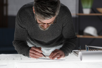 Architect drawing blueprints in office. Engineer sketching a construction project. Architectural plan. Close-up portrait of handsome bearded man concentrated on work. Business construction concept.