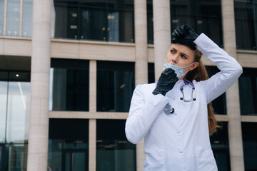 Tired girl doctor takes off medical mask. The concept of doctor after a major operation