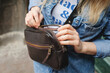 © Silver - Dark brown leather bag. The girl takes something out of the bag. Leather Cross Body Bags For Women. Close-up.