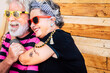 © simona - No limit age with nice and funny elderly caucasian couple have fun and smile in a portrait with wooden background - trendy and coloured accessories on old cheerful and happy people