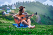 © Goffkein - Young happy inspired hipster woman traveler with guitar while traveling to the mountains