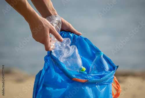 Fotografía Hand picking up plastic bottles into blue trash bag