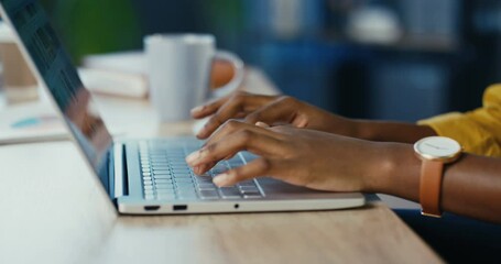 close up shot of african american female hands typing on laptop while sitting at office desk indoors
