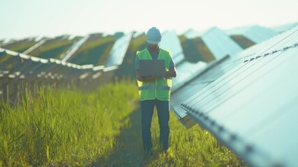 Attractive engineer working use laptop stand near solar batteries construction renewable power worker man technology modern electricity energy slow motion