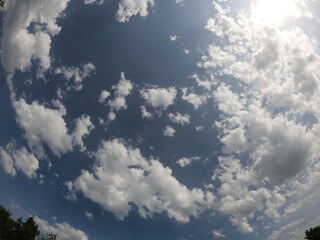 blue sky with white clouds and a bright sun