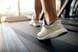 © Drazen - Close-up of athletic woman exercising on treadmill in a gym.