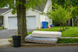 © ALAN - Two old worn out mattresses by a tree at the curb near a trash can in front of a house