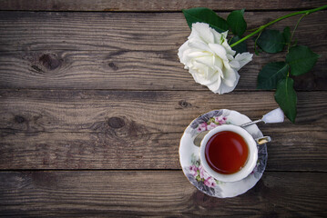 Canvas Print - White rose and a cup of tea on a wooden background