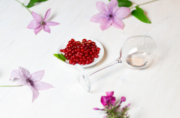 Wall Mural - Laying glass of rose wine on white wooden table, flowers, berries