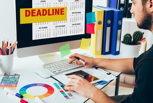 Young Handsome Graphic designer using graphics tablet looking on calendar with deadline date