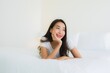 © siraphol - Portrait beautiful young asian woman relax happy smile on bed with white pillow blanket