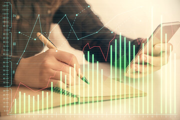 Double exposure of forex graph sketch hologram and woman holding and using a mobile device. Stock market concept.