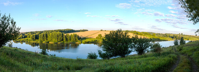  Sunny summer panoramic rural landscape.Beautiful view of river and golden wheat fields during sunrise.