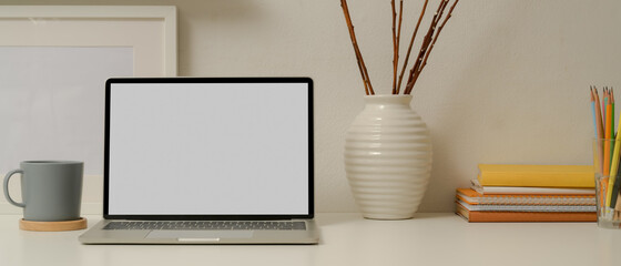 Modern study table with mock up laptop, stationery, books and decorations on white table